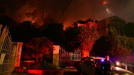 Un policier devant une maison près de Hollywood Boulevard, à Los Angeles, en proie à de gros incendies en janvier 2025. (ROBYN BECK / AFP)