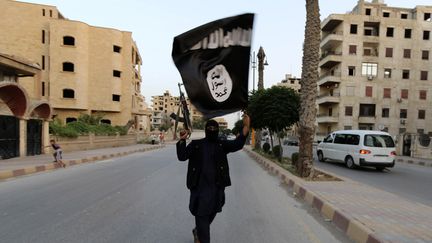 Un homme agite un drapeau de l'organisation Etat islamique dans les rues de Raqqa (Syrie), le 29 juin 2014. (REUTERS)