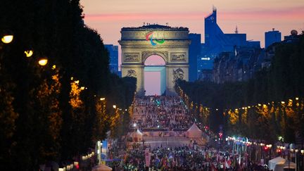 Des athlètes de différentes délégations défilent sur l'avenue des Champs-Elysées avec l'Arc de Triomphe en arrière-plan, lors de la cérémonie d'ouverture des Jeux Paralympiques de Paris 2024, à Paris, le 28 août 2024. (DIMITAR DILKOFF / AFP)