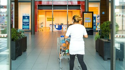 Une femme pousse son caddie à l'entrée d'un centre-commercial à Montauban (Tarn-et-Garonne), le 1er septembre 2021. (PATRICIA HUCHOT-BOISSIER / HANS LUCAS / AFP)