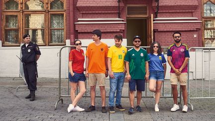 Les six militants qui participent au projet "The Hidden Flag" posent devant un policier, à Moscou (Russie), le week-end du 30 juin 2018. (JAVIER TLES / THE HIDDEN FLAG)