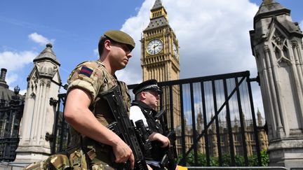 Un militaire patrouille aux côtés d'un policier a proximité du Parlement britannique, à Londres, le 24 mai 2017. (JUSTIN TALLIS / AFP)