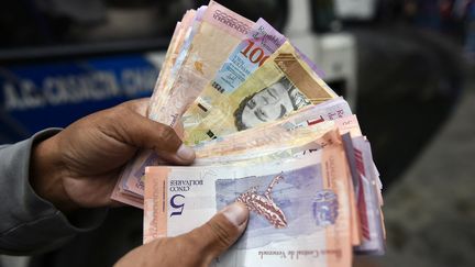 Un homme tient une liasse de billets en bolivars, le 29 janvier 2019 à Caracas (Venezuela). (LUIS ROBAYO / AFP)