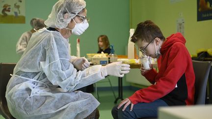 Un enfant donne un échantillon pour un test salivaire au centre éducatif de Lavoncourt, dans l'est de la France, le 1er mars 2021. (SEBASTIEN BOZON / AFP)