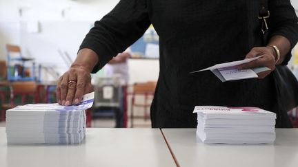 Une électrice saisit des bulletins de vote lors du second tour des élections législatives à Saint-Denis-de-la-Réunion, le 18 juin 2017. (RICHARD BOUHET / AFP)