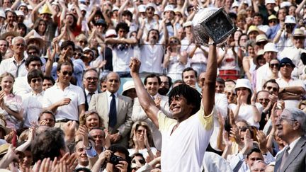 Yannick Noah tient son trophée après avoir battu le Suédois Mats Wilander et remporté les Internationaux de France de tennis, à Roland-Garros à Paris, le 5 juin 1983. (STF / AFP)