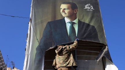 Un combattant rebelle détruit un portrait de l'ancien président syrien Bachar al-Assad à Alep (Syrie), le 30 novembre 2024. (MOHAMMED AL-RIFAI / AFP)