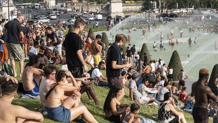 Des Parisiens prennent le soleil sur la place du Trocadéro, le 25 juil 2019, alors que la température dépasse les 42 degrés.&nbsp; (SAMUEL BOIVIN / NURPHOTO / AFP)