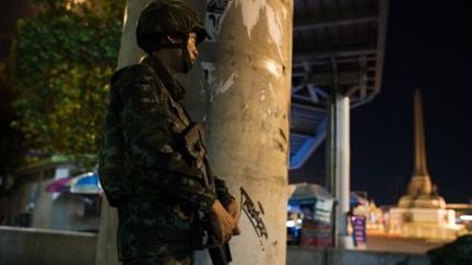 Un soldat monte la garde pendant le couvre-feu imposé par l'armée thaïlandaise, près du Monument de la Victoire à Bangkok le 25 mai 2014. (NICOLAS ASFOURI / AFP)