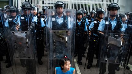 Une manifestante est assise devant les rangées de policiers anti-émeutes en signe de protestation. (PHILIP FONG / AFP)