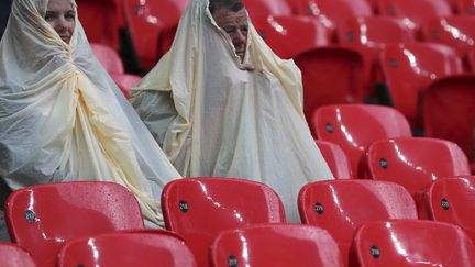 Deux spectateurs sous la pluie lors du match de football Senegal-Uruguay le 29 juillet 2012, troisi&egrave;me journ&eacute;e des Jeux olympiques. (SERGIO MORAES / REUTERS)