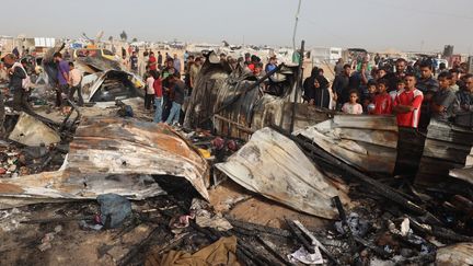 Des civils palestiniens devant des débris après une frappe israélienne sur un camp de déplacés à Rafah, dans le sud de la bande de Gaza, le 27 mai 2024. (EYAD BABA / AFP)