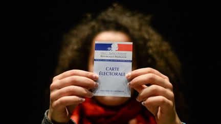 Une femme tient une carte d'électeur, à Besancon (Doubs), le 19 mars 2017. (SEBASTIEN BOZON / AFP)