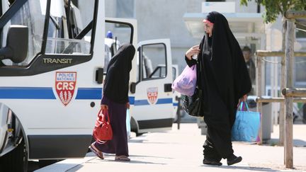 Deux femmes passent devant des v&eacute;hicules de CRS &agrave; Trappes (Yvelines), le 20 juillet 2013. (MAXPPP)