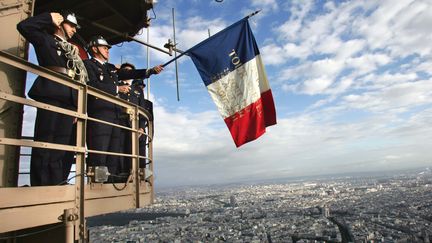 Des pompiers brandissant le drapeau français, en haut de la tour Eiffel à Paris, le 25 août 2004. (PIERRE VERDY / AFP)