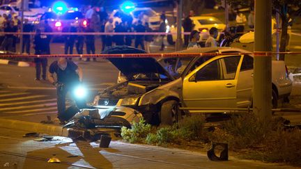 Des policiers isra&eacute;liens examinent la voiture qui a fonc&eacute; sur des pi&eacute;tons pr&egrave;s d'une station de tramway &agrave; J&eacute;rusalem (Isra&euml;l), faisant un mort et neuf bless&eacute;s, le 22 octobre 2014. (MENAHEM KAHANA / AFP)