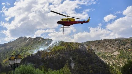 Un hélicoptère de la Sécurité civile largue de l'eau sur un incendie à Rigaud, au nord de Nice, le 3 août 2017. (YANN COATSALIOU / AFP)