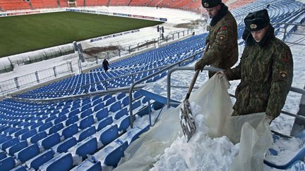 Des soldats enl&egrave;vent la neige des tribunes du stade du BATE Borisov, en Bi&eacute;lorussie, avant un match de Ligue des champions, le 25 novembre 2008. (SERGEI GRITS/AP/SIPA / AP)