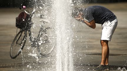 Un homme se rafraîchit près d'une fontaine sur la place Castello de Turin, en Italie,&nbsp;mercredi 2 août 2017. (MARCO BERTORELLO / AFP)