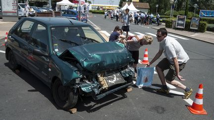 Des automobilistes observent une reconstitution d'accident pr&eacute;sent&eacute;e par des sapeurs-pompiers, le 29 juin 2012 sur l'aire de M&acirc;con Saint-Albain&nbsp;(Sa&ocirc;ne-et-Loire), sur l'autoroute A6.&nbsp; (JEAN-PHILIPPE KSIAZEK / AFP)