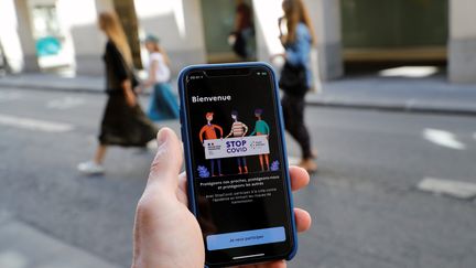 Un homme avec un téléphone dans la main sur lequel est lancé l'application StopCovid, le 27 mai 2020, à Paris. (THOMAS SAMSON / AFP)