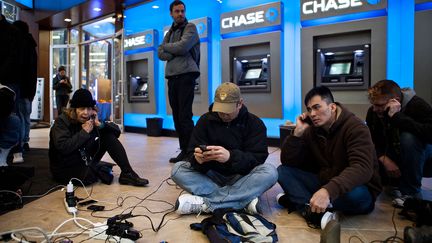 Certains new-yorkais victime de ces coupures d'&eacute;lectricit&eacute; se retrouvent dans des banques et des magasins qui mettent des multiprises &agrave; leur disposition. (ANDREW BURTON / GETTY IMAGES NORTH AMERICA / AFP)