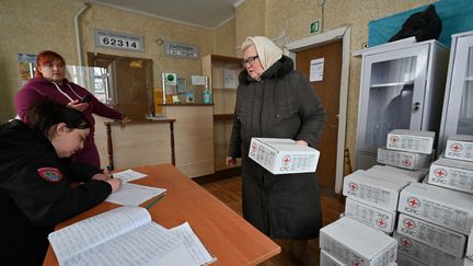 Une femme reçoit un colis d'aide humanitaire à Dubivka, un village privé d'électricité dans la région de Kharkiv, dans l'est de l'Ukraine, le 1er mars 2023. (SERGEY BOBOK / AFP)