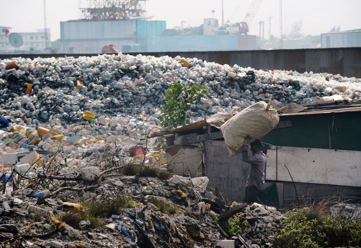 Un homme traverse des tonnes de d&eacute;chets accumul&eacute;s sur l'&icirc;le de Thilafushi, dans l'archipel des Maldives, le 6 septembre 2013. (ROBERTO SCHMIDT / AFP)