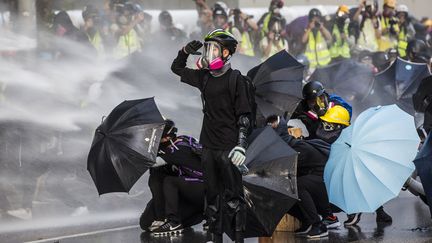 Des manifestants opposés à l'influence de Pékin défient les canons à eau de la police devant le siège du gouvernement, le 15 septembre 2019 à Hong Kong. Parties en mars d'une protestation contre une loi autorisant l'extradition en Chine continentale de citoyens condamnés dans l'archipel, les manifestations ont depuis pris une ampleur bien plus importante. La plupart des opposants réclament désormais un suffrage universel direct et une indépendance totale vis-à-vis de Pékin. (ISAAC LAWRENCE / AFP)