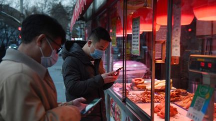 Des passants portent des masques à Pékin, le 25 février 2020.&nbsp; (GREG BAKER / AFP)