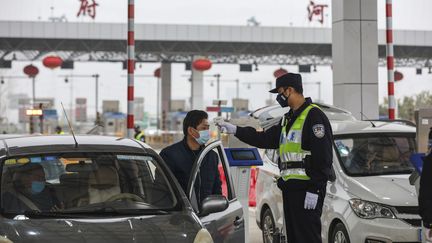 Un policier prend la température d'un automobiliste, le 24 janvier 2020 à Wuhan (Chine). (AFP)