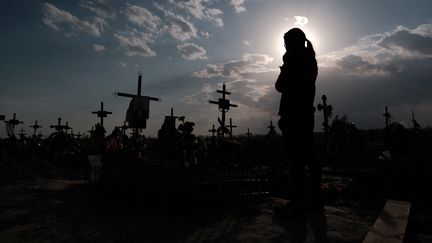 Une femme se recueille&nbsp;sur la tombe de son mari à Boutcha (Ukraine), le 12 mai 2022. (HIROTO SEKIGUCHI / YOMIURI / AFP)