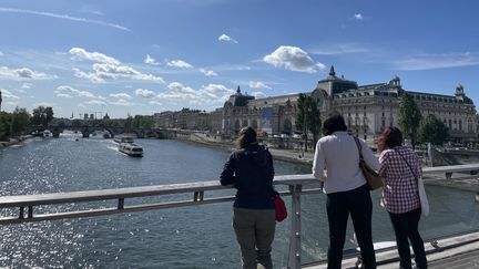 Lundi 17 juillet 2023, des spectateurs curieux jettent un oeil au défilé des bateaux sur la Seine à l'occasion du test technique préalable à la cérémonie d'ouverture des Jeux olympiques de Paris, prévue le 26 juillet 2024. (Clément Mariotti Pons)