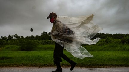 Un homme marche sous la pluie, le 27 août 2021, à&nbsp;Batabano sur l'île de Cuba. (YAMIL LAGE / AFP)