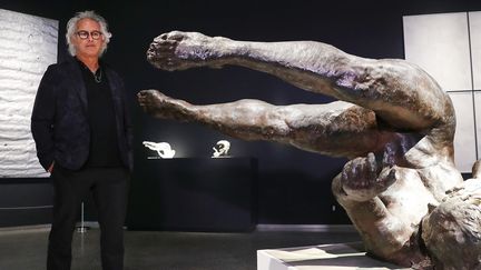 L'artiste Eric Fischl pose près de son oeuvre "Tumbling Woman", statue représentant une femme tombant à terre, la main tendue.
 (SPENCER PLATT / GETTY IMAGES NORTH AMERICA / AFP)