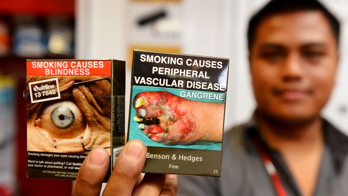 Un vendeur pr&eacute;sente les nouveaux paquets de cigarettes en circulation en Australie, le 1er d&eacute;cembre 2012. (WILLIAM WEST / AFP)