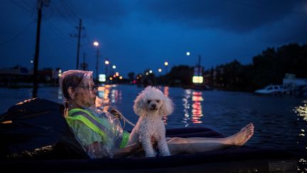 Une habitante de Houston et son chien flottent sur un matelas gonflable, lors des inondations de la première nuit de tempête. (ADREES LATIF / REUTERS)