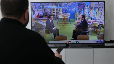 Un homme regarde le président de la République Emmanuel Macron invité du journal de 13 heures jeudi 12 avril 2018. (MAXPPP)