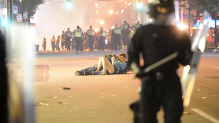 Un jeune homme r&eacute;conforte sa petite amie bless&eacute;e pendant des &eacute;meutes &agrave; Vancouver (Canada), le 15 juin 2011. (RICH LAM / GETTY IMAGES)