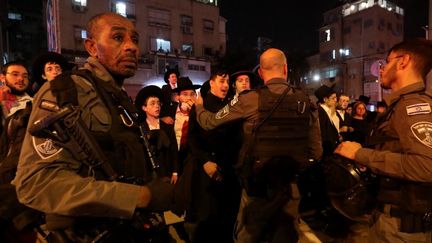 Des forces de sécurité israéliennes empêchent des habitants de s'approcher des lieux d'une fusillade, le 29 mars 2022 à Bnei Brak, à 7 km à l'est de Tel-Aviv. (GIL COHEN-MAGEN / AFP)