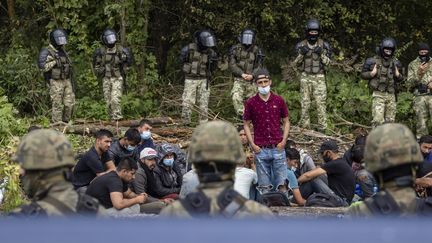 Un groupe de migrants encerclé par des militaires, le 20 août à la frontière entre la Pologne et la Biélorussie. (WOJTEK RADWANSKI / AFP)