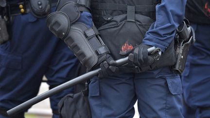 The baton of a French police officer is pictured as police face dockers demonstrating against the labour law reform and the ecologic transition on the sidelines of the inauguration of the first French offshore wind turbine, FLOATGEN, on October 13, 2017 in Saint-Nazaire, western France. - The first wind turbine to be located at sea in France was inaugurated on October 13 in the port of Saint-Nazaire, where it was assembled on land, before soon being towed and put into service off Le Croisic. (Photo by LOIC VENANCE / AFP) (LOIC VENANCE / AFP)