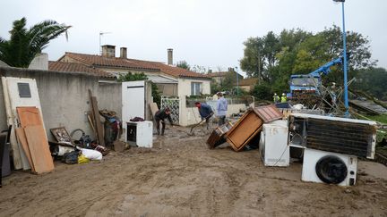 Des résidents nettoient les dégâts causés par les inondations à&nbsp;Villegailhenc (Aude), le 17 octobre 2018. (ERIC CABANIS / AFP)