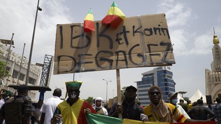 Des manifestants qui brandissent une pancarte appelant le régime du président malien à "dégager" le 5 juin 2020 dans le cadre d'un rassemblement organisé à Bamako par une coalition dont fait partie le mouvement de l'imam Mahmoud Dicko.&nbsp; (MICHELE CATTANI / AFP)