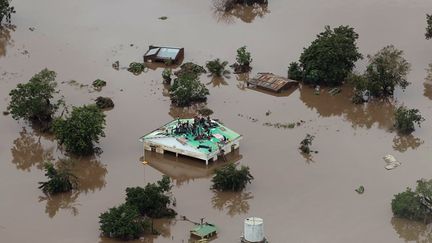 A Beira, au Mozambique,&nbsp;des habitants sont réfugiés sur le toit d'une maison, dans un quartier inondé au passage d'Idai, le 18 mars 2019. (RICK EMENAKET / MISSION AVIATION FELLOWSHIP / AFP)