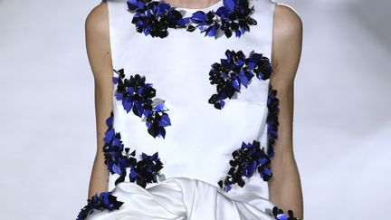 Chez l'Italien Giambattista Valli, ici encore, des fleurs, surtout les bleuets, brodées ou imprimées. Le défilé commence avec des robes très courtes, assez près du corps, avec jupes corolles ou jupes noeuds. Pour le soir, le couturier reprend les jupes noeuds, mais il les allonge. Il propose aussi une robe bustier en satin duchesse ivoire avec un imprimé de bleuets. Elle est fendue tout au long de la jambe mais se porte avec une très mini-jupe pour rester "preppy". 
 (PATRICK KOVARIK / AFP)