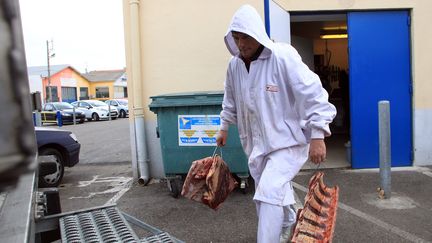 Un employ&eacute; r&eacute;quisitionn&eacute; transporte des viandes suspectes, le 16 d&eacute;cembre &agrave; Narbonne (Aude).&nbsp; (RAYMOND ROIG / AFP)