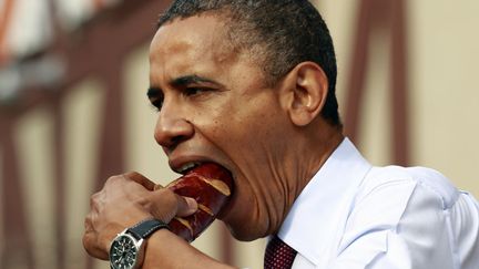 Le pr&eacute;sident am&eacute;ricain, Barack Obama, mord dans une bratwurst (saucisse allemande) en visite &agrave; Milwaukee (Wisconsin), le 22 septembre 2012. (KEVIN LAMARQUE / REUTERS)