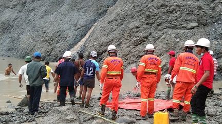 Des pompiers tentent de porter secours à des mineurs emportés par un glissement de terrain causé par la mousson, le 2 juillet 2020 à&nbsp;Hpakant, en Birmanie. (HANDOUT / MYANMAR FIRE SERVICES DEPARTMENT / AFP)