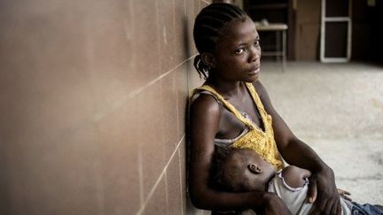 Une jeune Libérienne de 16 ans et sa petite fille dans le bidonville de West Point, dans la banlieue de la capitale Monrovia.   (MARCO LONGARI / AFP)